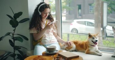 Kafede akıllı telefon okşayarak pet kullanarak müzik dinlekulaklık kadın