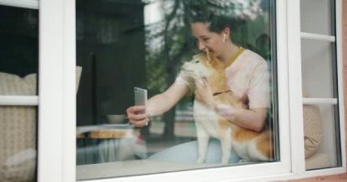 Pencere eşik kafede akıllı telefon kullanarak köpek ile selfie çeken güzel kız