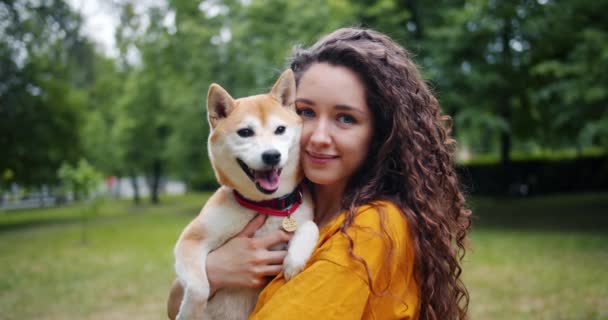 Πορτρέτο του όμορφο κορίτσι αγάπη ιδιοκτήτη σκύλου στέκεται στο πάρκο με το όμορφο κατοικίδιο ζώο της χαμογελά — Αρχείο Βίντεο