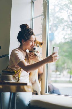 Sevimli kadın alma selfie ile Shiba inu köpek oturma üzerinde pencere eşik içinde Cafe