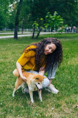 Yeşil çim üzerinde parkta Shiba inu köpek dokunmadan güzel genç kadın
