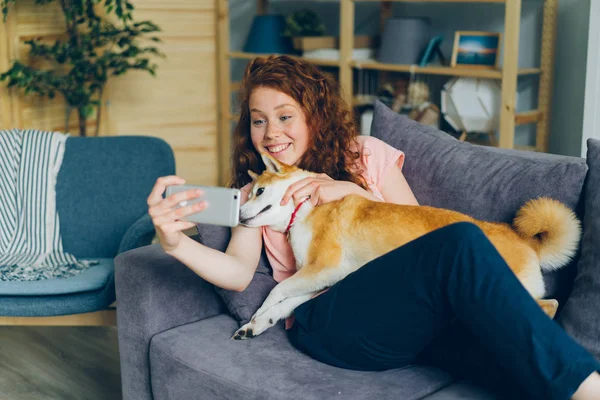 Νέος ιδιοκτήτης σκύλου παίρνοντας selfie με το κατοικίδιο ζώο χαμογελώντας χρησιμοποιώντας κάμερα smartphone στο σπίτι — Φωτογραφία Αρχείου