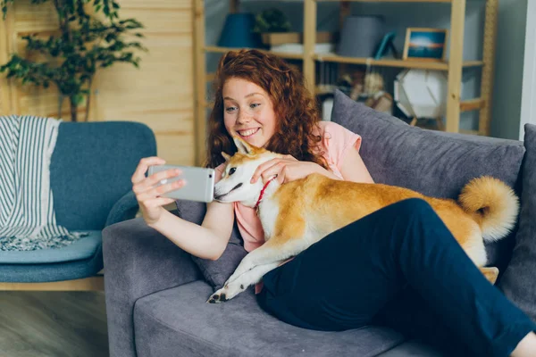 Jeune propriétaire de chien prenant selfie avec animal souriant à l'aide d'une caméra smartphone à la maison — Photo