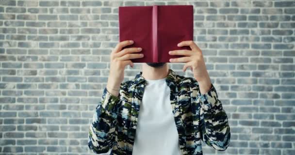 Retrato de livro de leitura estudante cansado, em seguida, fazendo engraçado rosto rolando os olhos — Vídeo de Stock