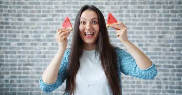 Young woman holding watermelon hiding eyes smiling on brick wall background — Stock Video