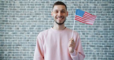 Tuğla duvar arka planda uçan Abd bayrağı tutan gururlu Amerikalı adam Portresi