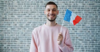 Tuğla duvar arka plan üzerinde Fransız ulusal bayrağı ile mutlu genç adamın portresi