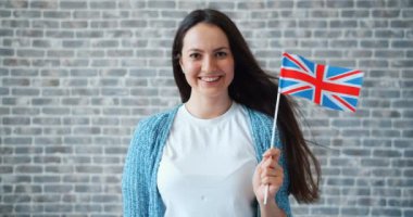 Tuğla duvar arka plan üzerinde İngiliz bayrağı ile güzel genç kadın Portresi