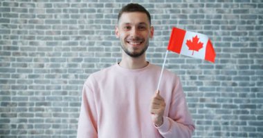 Tuğla duvar arka plan üzerinde Kanada bayrağı tutan neşeli öğrenci portresi
