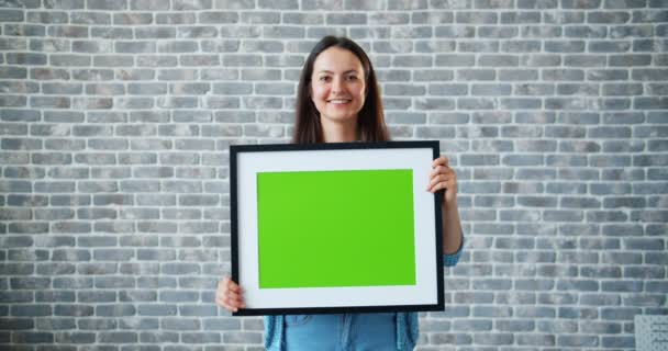 Portret van mooie meisje houden groene Chroma Key mockup foto en glimlachend — Stockvideo