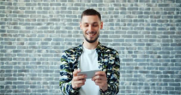 Retrato de homem bonito desfrutando de videogame na tela de toque do smartphone — Vídeo de Stock