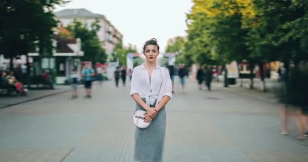 Vergrößern im Zeitraffer einer ernsten Frau in Freizeitkleidung, die in einer belebten Straße steht — Stockvideo