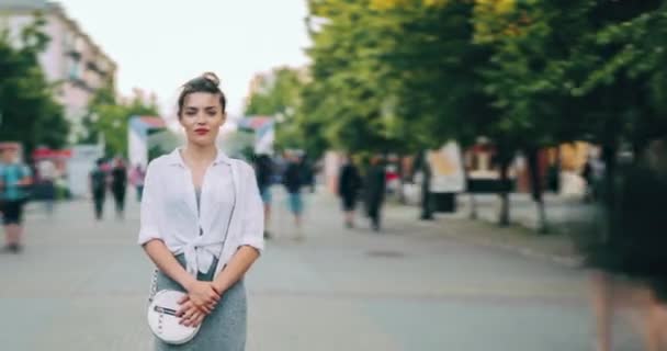 El lapso de tiempo de la chica en la ropa moderna mirando a la cámara de pie en la calle de la ciudad — Vídeos de Stock