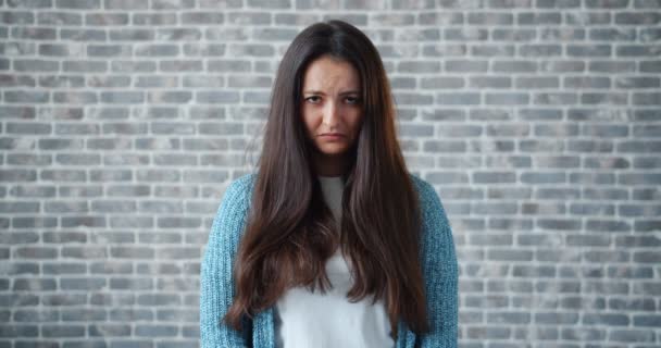 Porträt einer aufgebrachten Dame, die sich mit traurigem Gesicht auf Backsteinhintergrund umsieht — Stockvideo