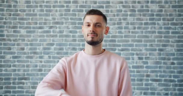 Portrtait of disappointed guy showing thumbs-down gesture on brick background — Stock Video