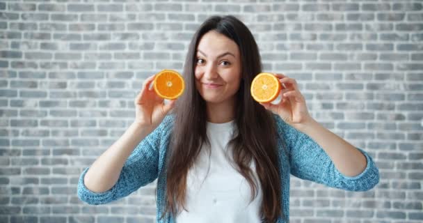 Retrato de la bella dama sosteniendo naranjas y sonriendo sobre fondo de pared de ladrillo — Vídeos de Stock