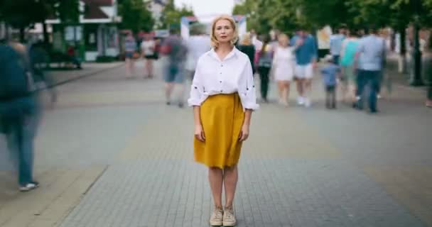 Χρονική λήξη της ώριμης γυναίκας που στέκεται στην πόλη σε πολυσύχναστο δρόμο κοιτάζοντας την κάμερα — Αρχείο Βίντεο