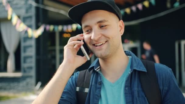 Pomalý portrét veselého muže, který mluví na mobilním telefonu venku na ulici — Stock video