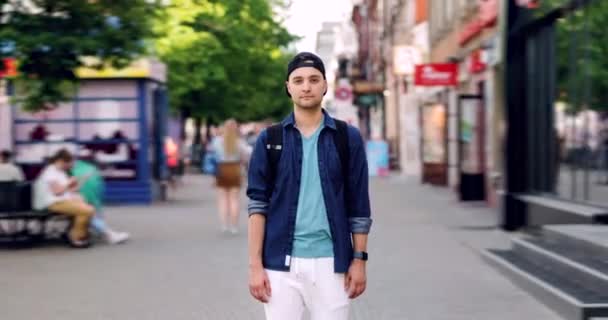 Pomniejszyć upływ czasu atrakcyjny facet z plecak stojący na zewnątrz w ulica — Wideo stockowe