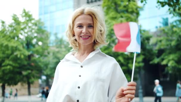 フランス国旗を持って屋外に立っている成熟した女性のスローモーションの肖像画 — ストック動画