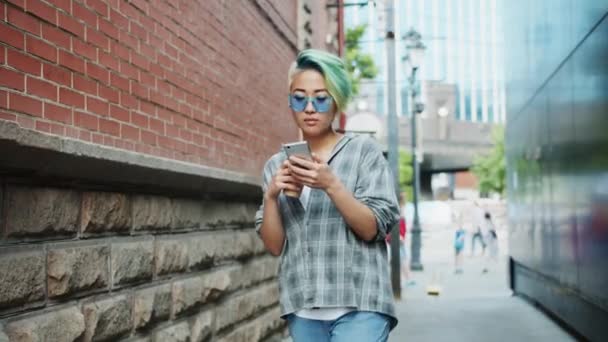 Cámara lenta de hipster asiático caminando con smartphone y sosteniendo para ir café — Vídeo de stock