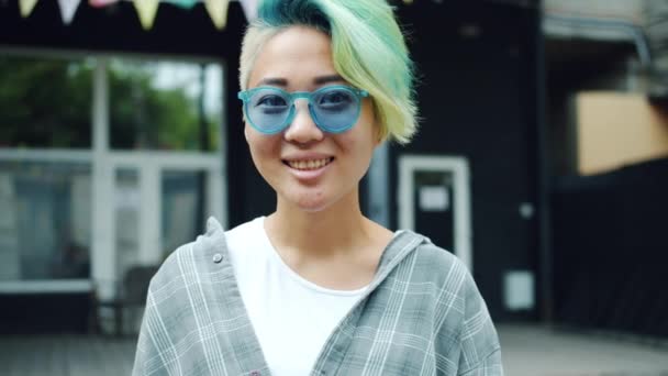 Portré divatos ázsiai lány mutatja ok kézmozdulattal, és mosolyogva a szabadban — Stock videók