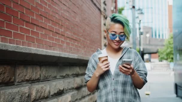 Slow motion ganska asiatisk kvinna gå utomhus med kaffe och smartphone — Stockvideo