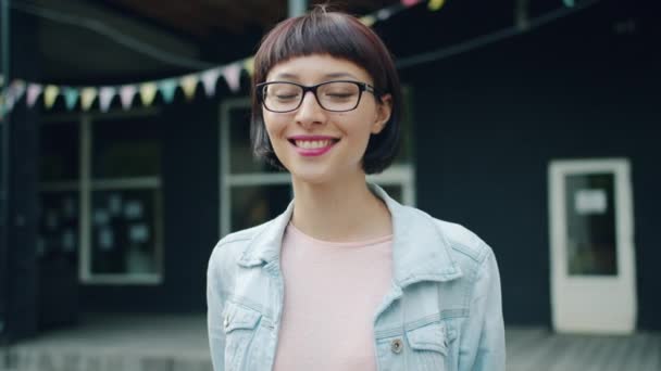 Retrato en cámara lenta de una joven morena mirando a la cámara y sonriendo al aire libre — Vídeos de Stock