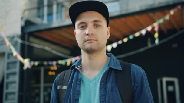 Portrét dobře vypadající mladého muže stojícího venku na ulici s vážnou tváří — Stock video