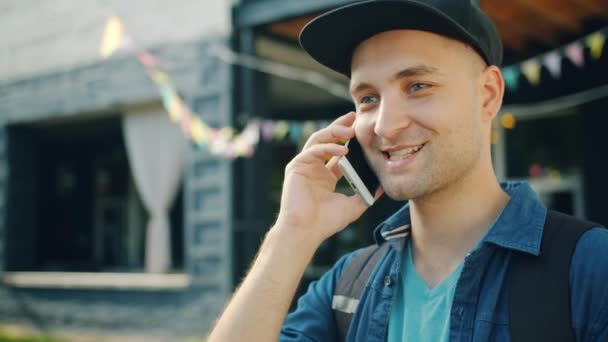 Portrait of handsome student talking on mobile phone outside in the street — Stock Video