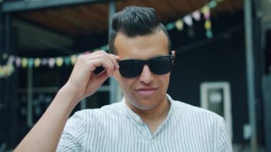 Sokakta gülümseyerek dışarıda güneş gözlüğü kaldıran Arap adamın portresi