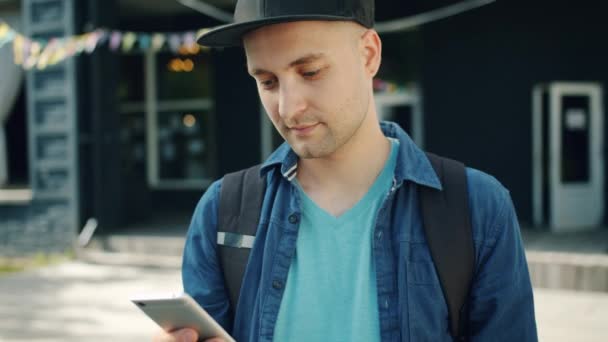 Retrato de joven atractivo usando la pantalla táctil del teléfono inteligente al aire libre — Vídeo de stock