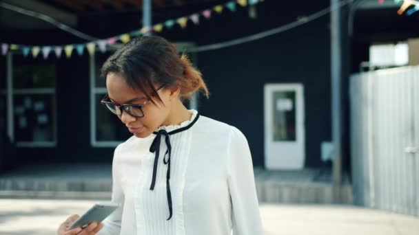 Vrolijke African American Girl met behulp van smartphone buitenshuis in straat aanraken scherm — Stockvideo