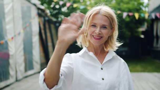 Lassú mozgás a mosolygó hölgy integetett kézzel üdvözölve állt a szabadban, a város — Stock videók