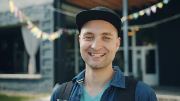Крупный план портрета радостного студента, улыбающегося, смеющегося на улице города — стоковое видео