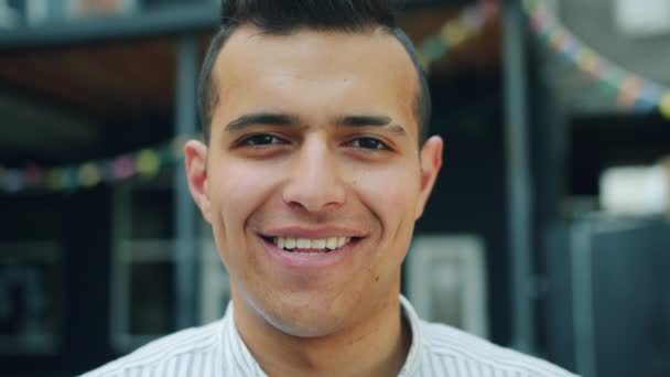 Primer plano retrato de atractivo joven árabe sonriendo mirando a la cámara al aire libre — Vídeos de Stock