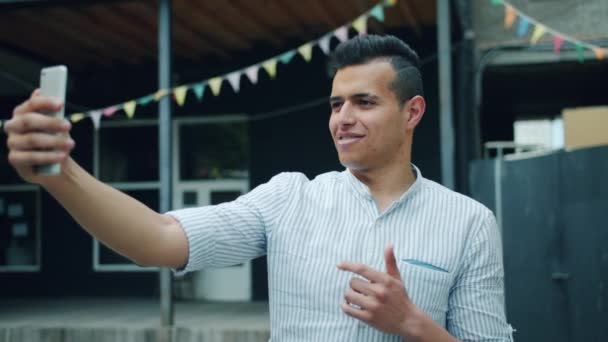 Retrato del alegre hombre de raza mixta tomando selfie al aire libre usando la cámara del teléfono inteligente — Vídeos de Stock