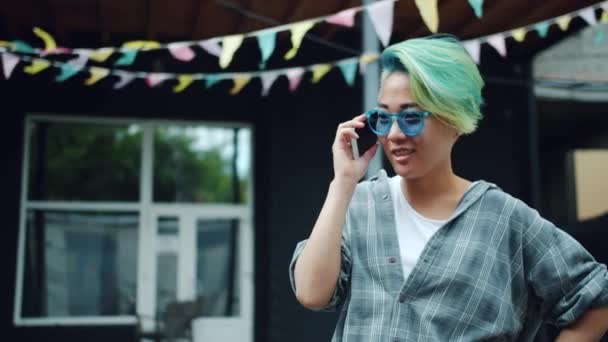 Mouvement lent de jolie asiatique fille hipster parler sur téléphone mobile à l'extérieur — Video