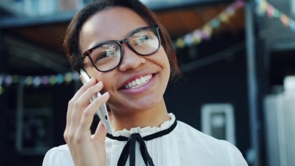 Крупним планом веселий афроамериканець дівчина говорити на мобільному телефоні на відкритому повітрі — стокове відео