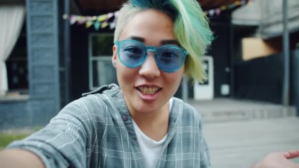 Cámara lenta de la mujer joven asiática haciendo videollamada en línea al aire libre — Vídeos de Stock