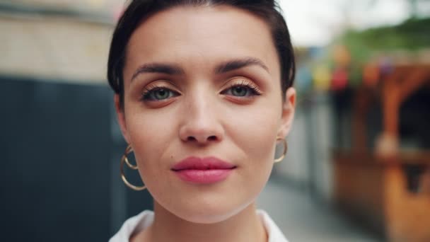 Close-up retrato de menina atraente olhando para a câmera com sorriso claro ao ar livre — Vídeo de Stock