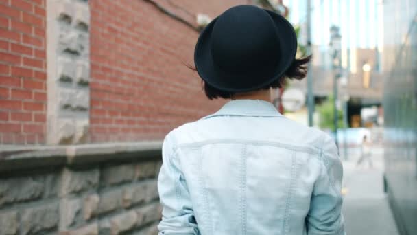 年轻女士在户外行走的慢动作，然后转向眨眼触摸帽子 — 图库视频影像