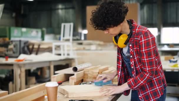 Junge Fabrikarbeiterin poliert Holz mit Schleifblock in der Werkstatt — Stockvideo