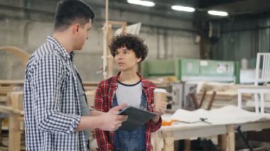 Neşeli erkek ve kadın kahve ve tablet tutan ahşap atölyesinde sohbet