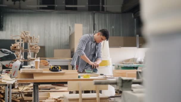 Trabajador de fábrica puliendo madera con máquina eléctrica en amplio taller — Vídeo de stock