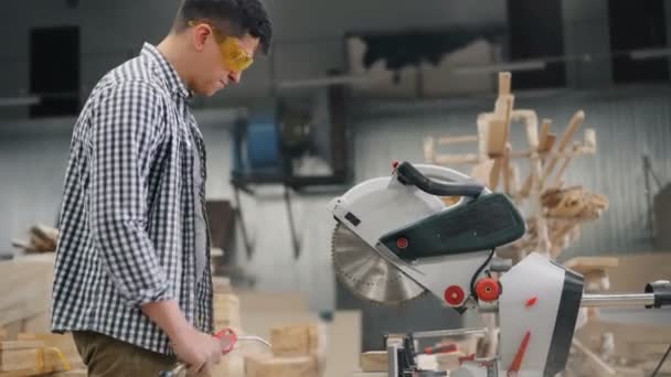 Trabajador en gafas usando compresor de aire para soplar serrín de sierra circular — Vídeos de Stock