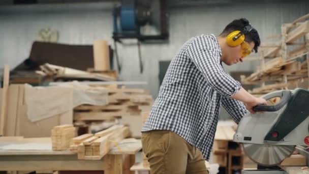 Man zagen hout in workshop met behulp van elektrische zaagwerken alleen het dragen van een bril — Stockvideo