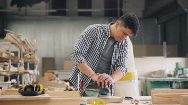 Trabajador de madera guapo utilizando la máquina de pulir para pulir madera en el taller — Vídeo de stock