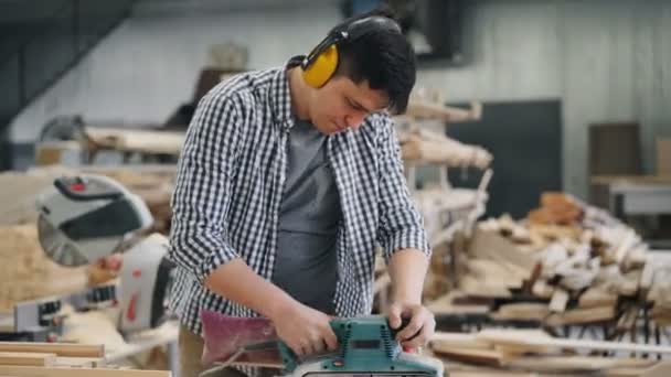 Zoom-out van mannelijke timmerman polijsten van hout met band Sander werken in de fabriek — Stockvideo