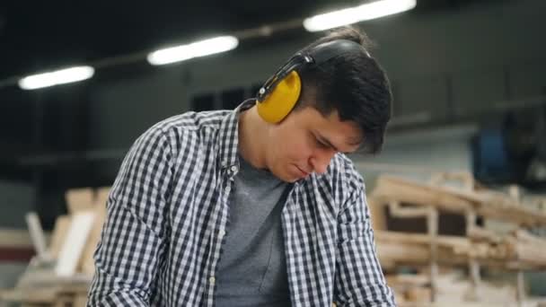 Hombre trabajador que utiliza la lijadora de cinta para pulir madera en el taller — Vídeo de stock